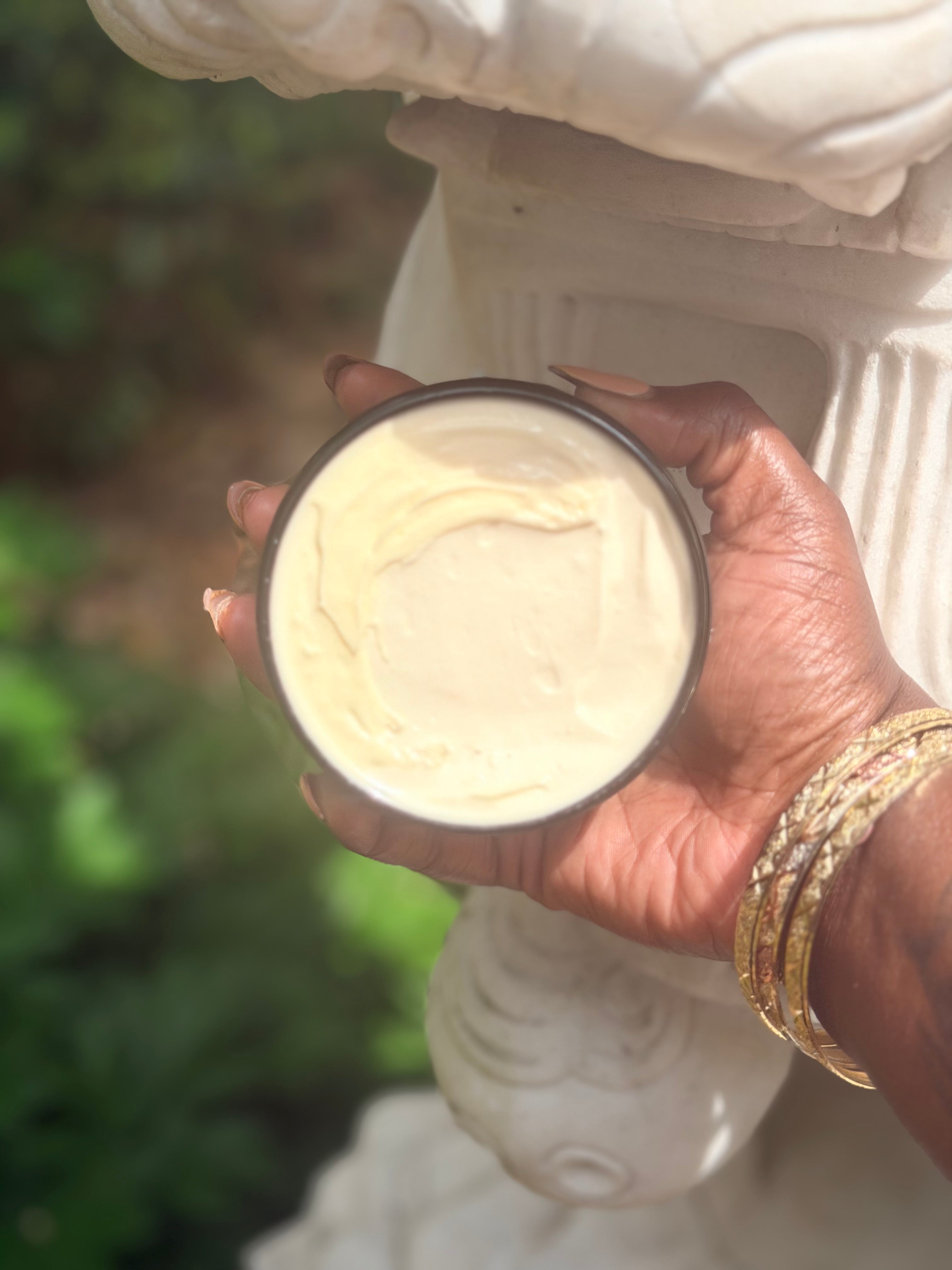 Hand holding a container of cream with a blurred natural background